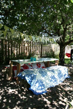 You don't need to spend a lot of money on backyard seating. Just line up some hay or straw bales, cover them with quilts and build a simple table using an old door and lumber scraps. Voila! A simple and stylish outdoor dining scene. (Megan Cooley)