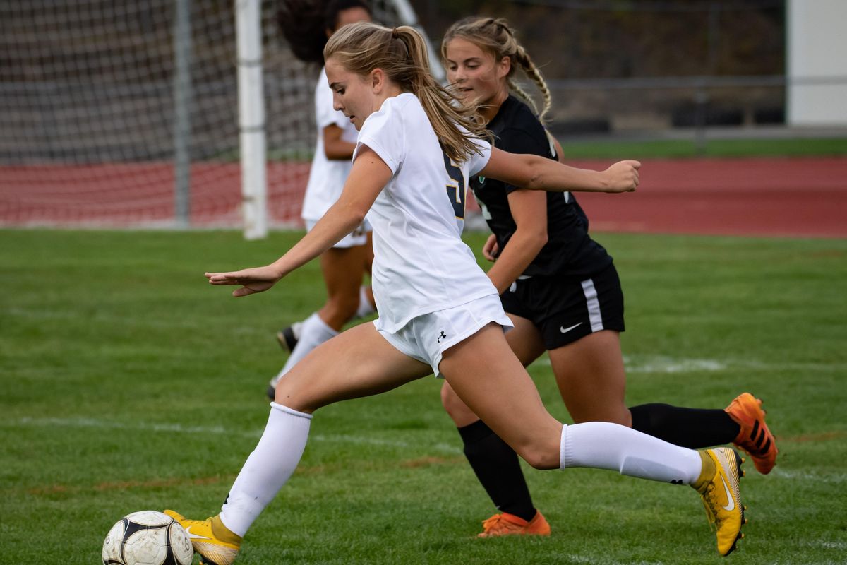 Mead senior forward Margo Schoesler  moves the ball downfield as East Valley’s Denise Cousins chases during a match on Tuesday, Sept. 10, 2019, at East Valley High School. (Colin Mulvany / The Spokesman-Review)